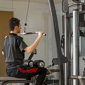 A man exercises on the lateral pulldown machine at the UCD Gym